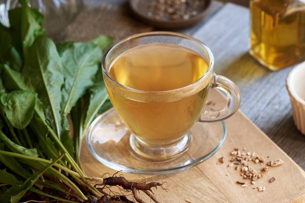 Dandelion root tea being prepared with dried dandelion roots, hot water, and a teapot